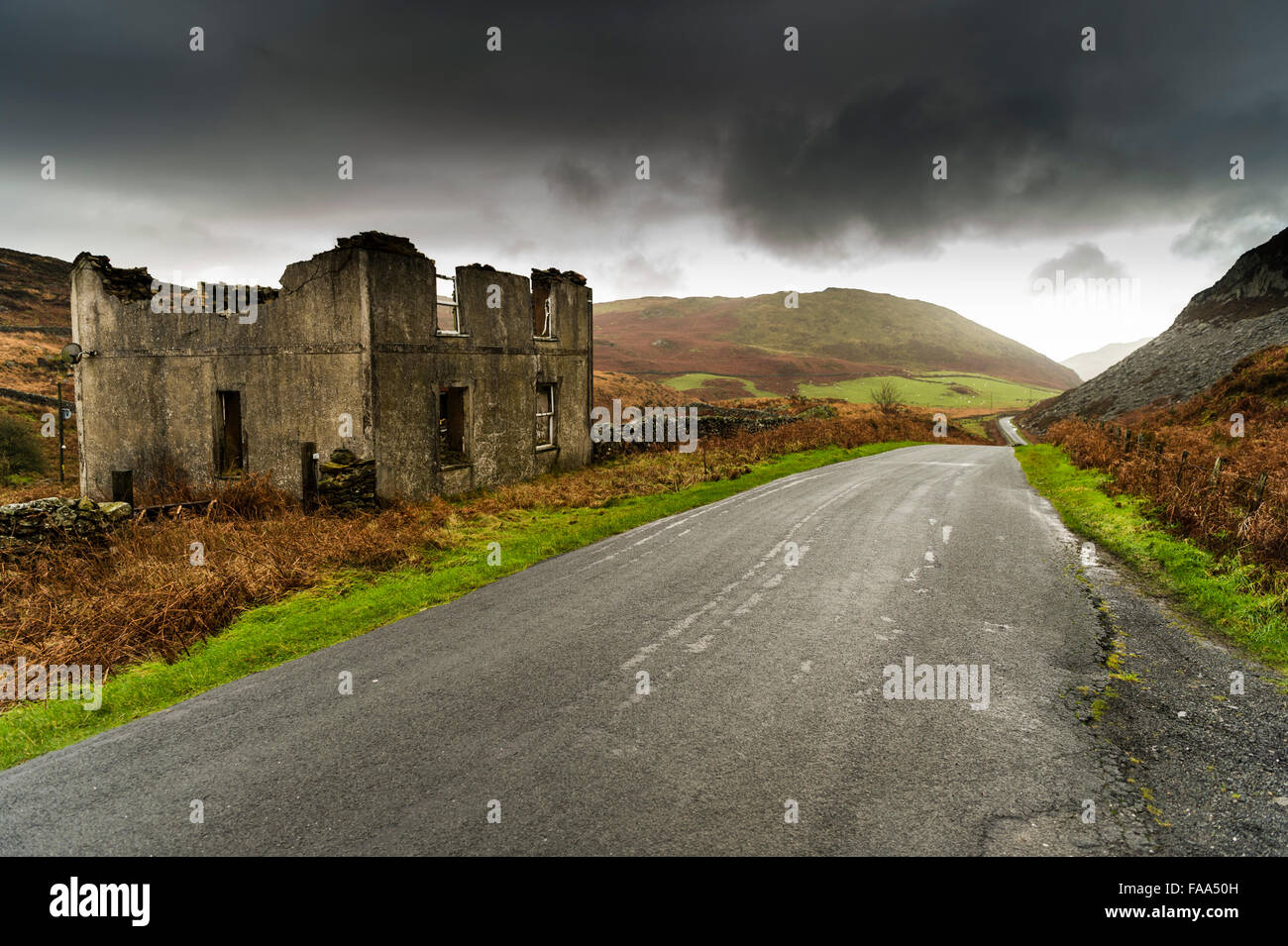 Entstelltes eines verlassenen und verfallenen Haus, neben einem schmalen Land Rennstreckenareal in einem abgelegenen Tal in Gwynedd, Wales UK Stockfoto