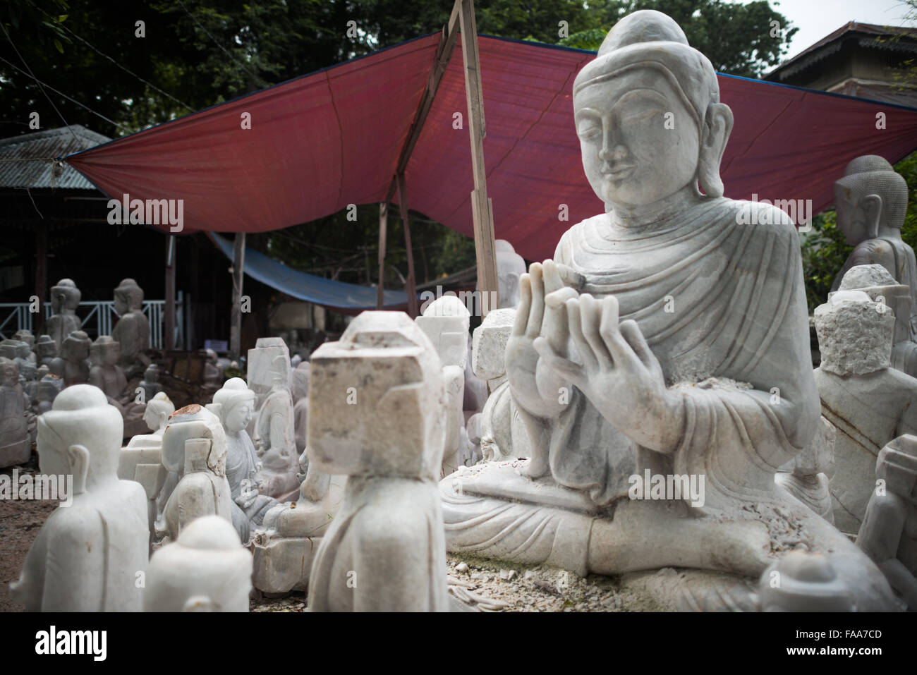 MANDALAY, Myanmar - lokale Handwerker der staubigen und Knochenarbeit der Carving Statuen des Buddha verpflichten sich aus Marmor. Mit dem Buddhismus, die vorherrschende Religion in Myanmar gibt es eine starke Nachfrage für die Statuen, mit Kunden in der Lage, aus einer Vielzahl von Posen, Größen und Stile zu wählen. Die Handwerker sind auf einer Straße in der Nähe von Mandalay Chanmyathazi in der Nähe der Mahamuni Pagode geclustert. Stockfoto