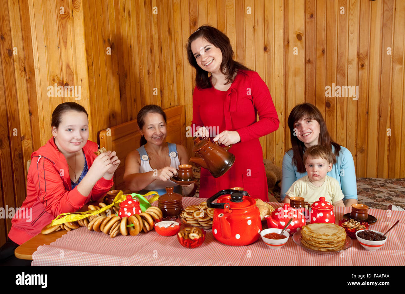 Frauen mit Kind trinkt Tee und isst Pfannkuchen in Haus Stockfoto