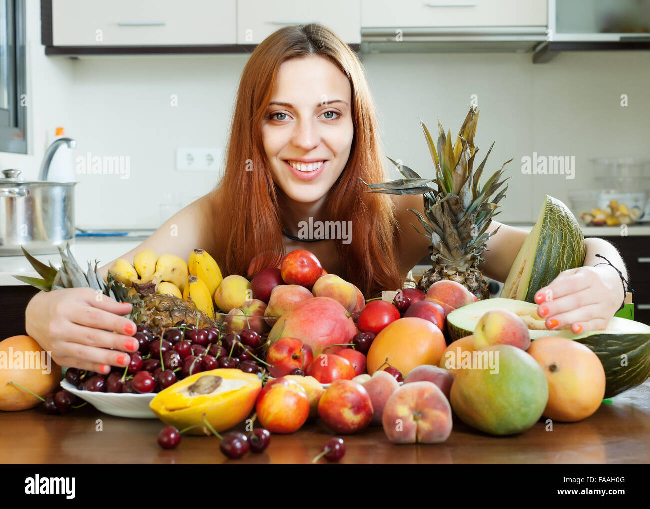 Glückliche junge Frau mit Haufen von Obst in der Küche zu Hause Stockfoto