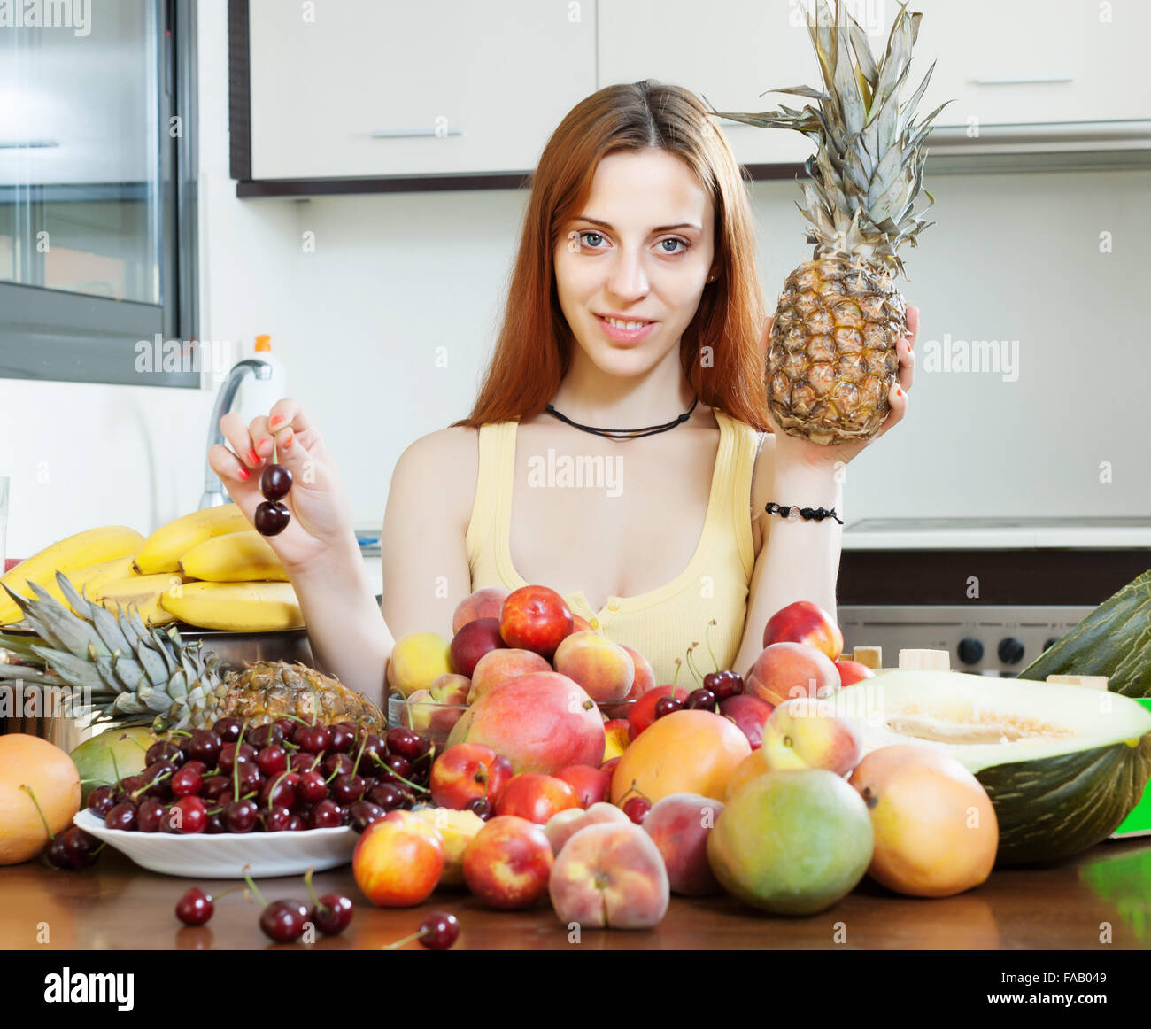 Langhaarige Frau mit Pinien und Haufen von Früchten Stockfoto