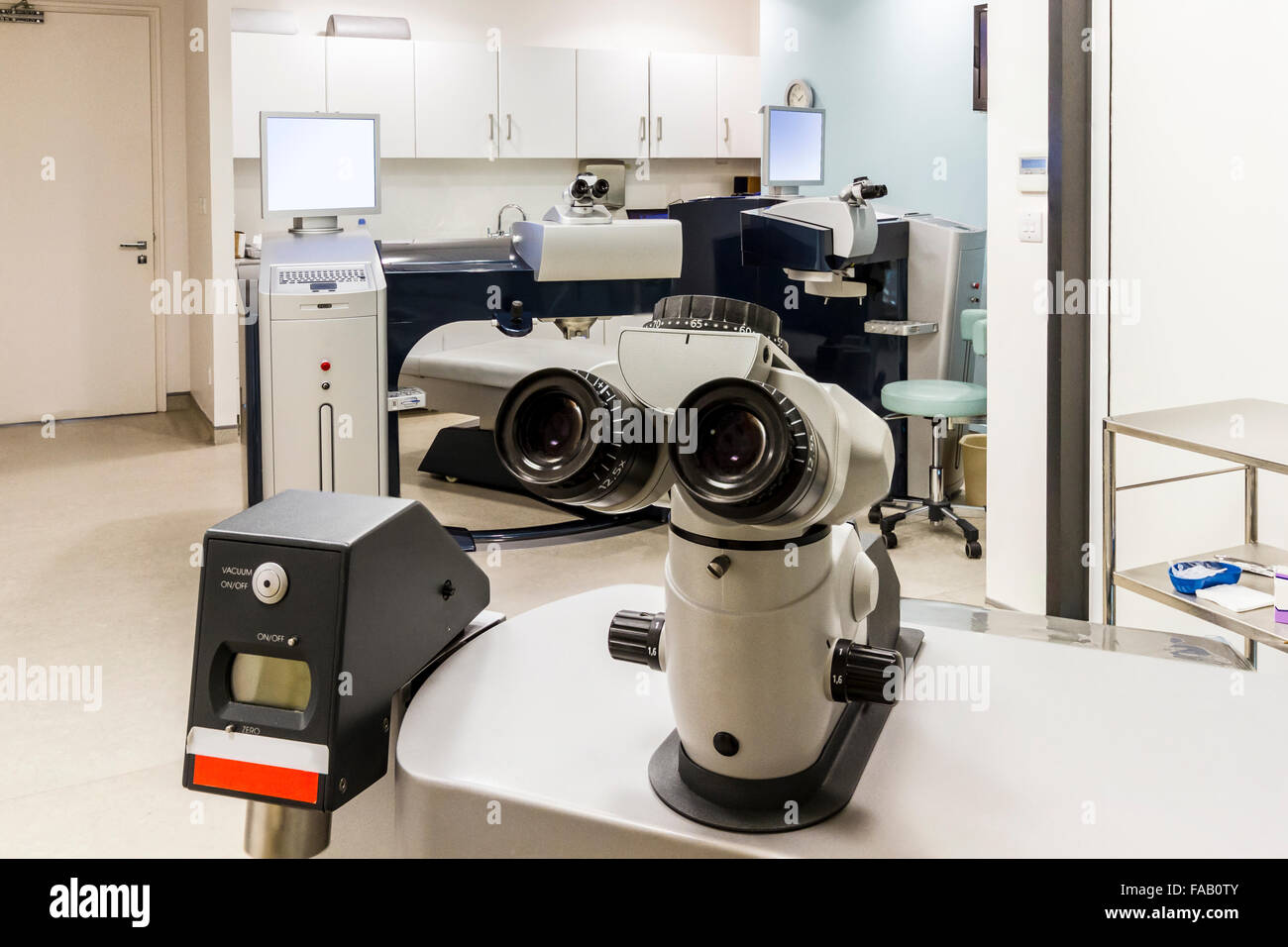Mikroskop und Lasek Maschinen in Augenklinik mit Tablett und Schränke an Wänden Stockfoto