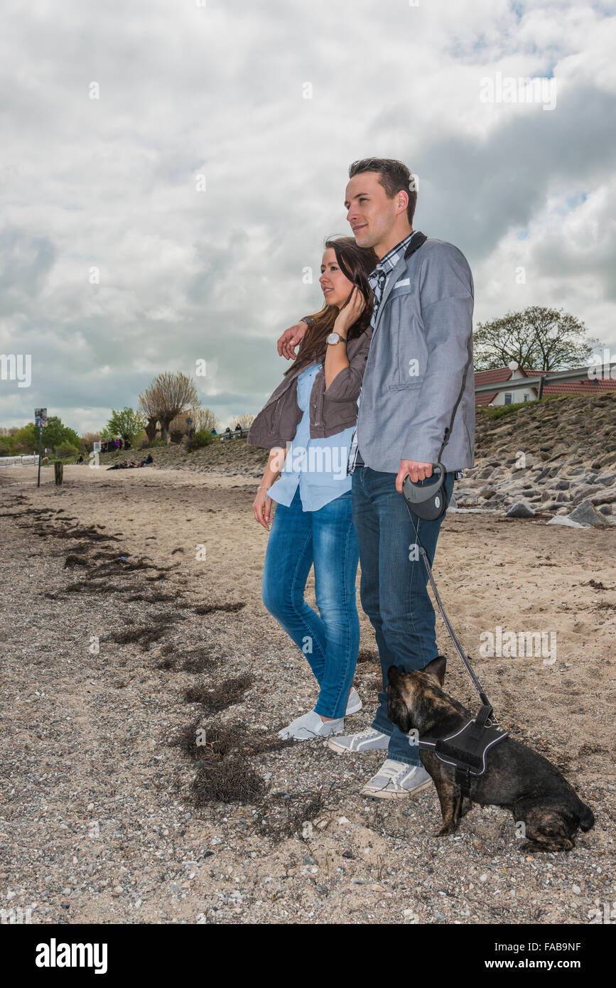 Paar, 25-30 Jahren, am Strand mit Hund Stockfoto
