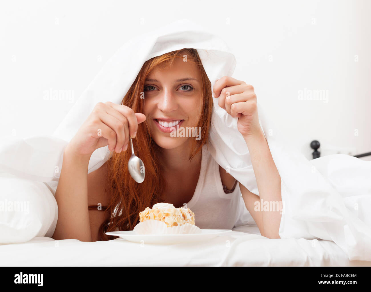Lächelndes Mädchen essen Keks in ihrem Bett zu Hause Stockfoto