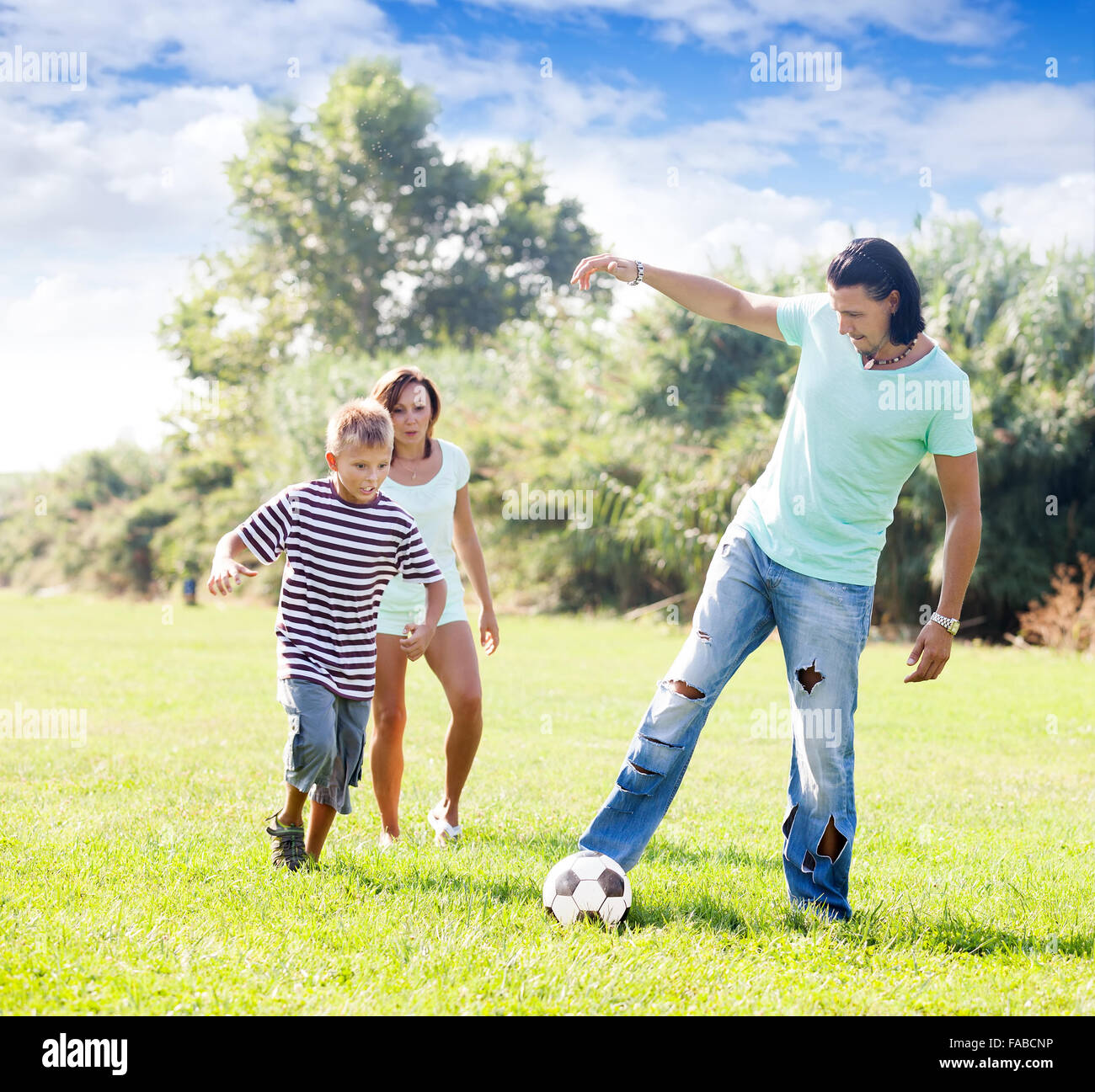 Glückliche Eltern mit Kind spielen mit Fußball im park Stockfoto