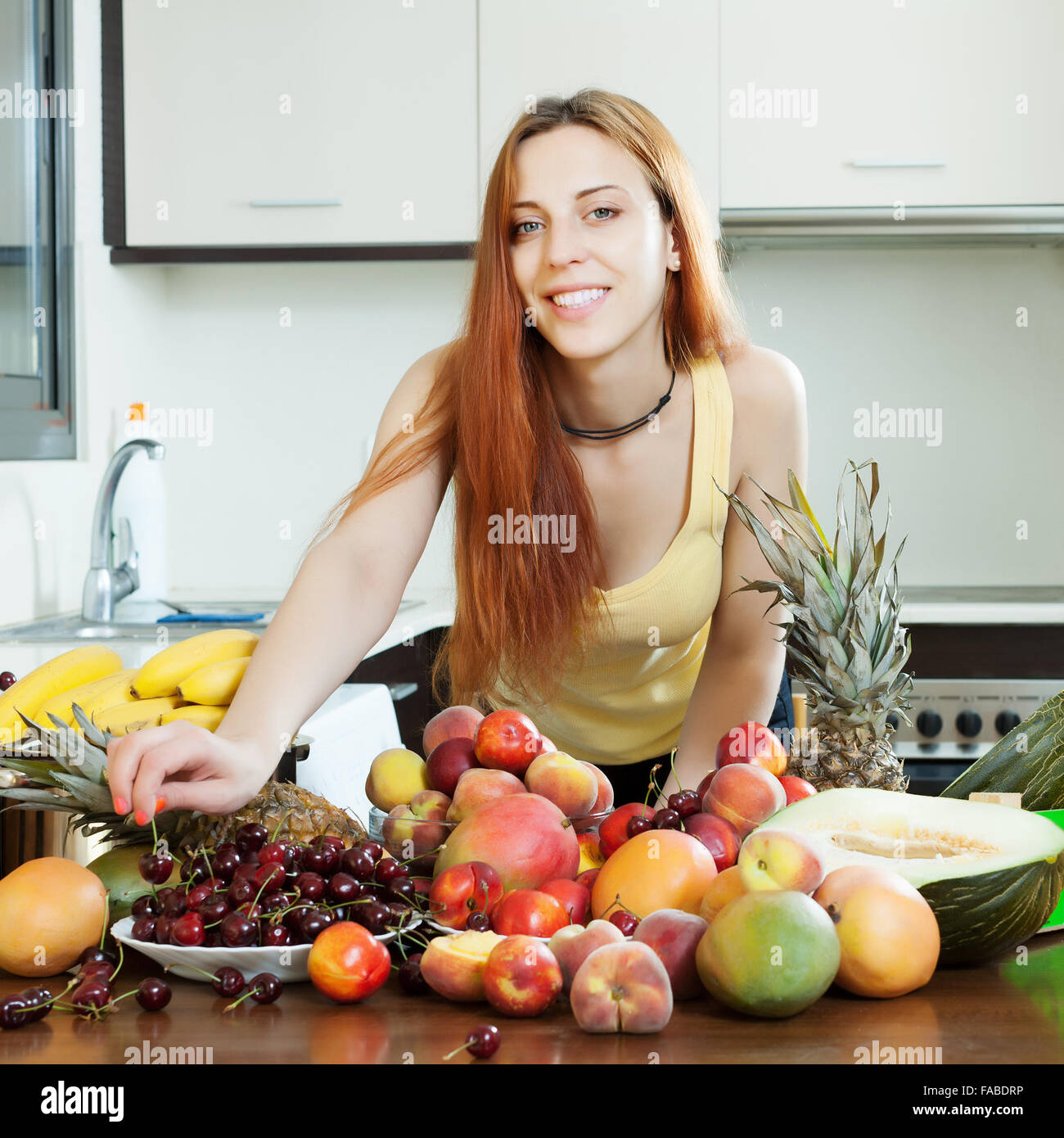 Positiven langhaarige Frau mit Haufen von reifen Früchten im Hause kitch Stockfoto