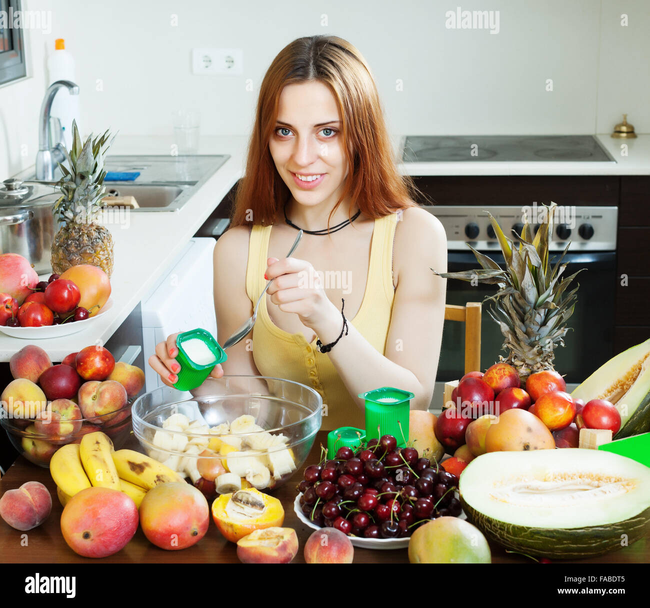 Frau macht Obstsalat mit Sahne in Küche Stockfoto