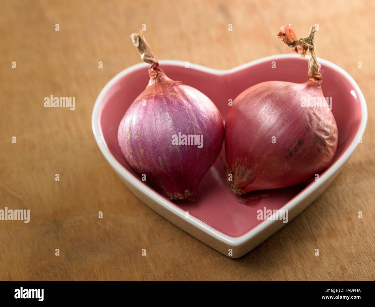 Zwiebel in einer Schüssel in Herzform Stockfoto