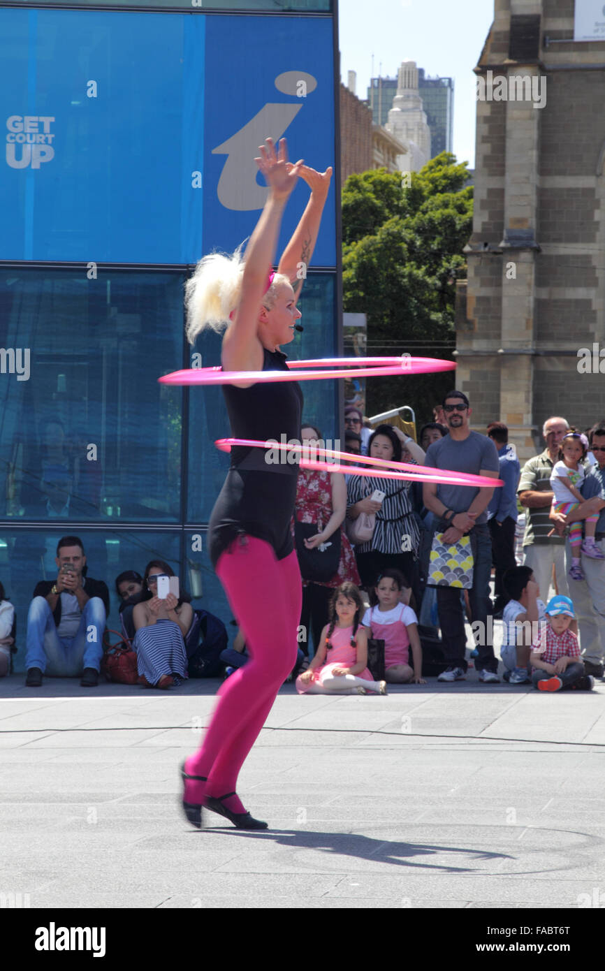Straßenkünstler zeigen eine Hula-hoop-Leistung am Federation Square in Melbourne, Victoria, Australien, an einem sonnigen Sommertag. Stockfoto