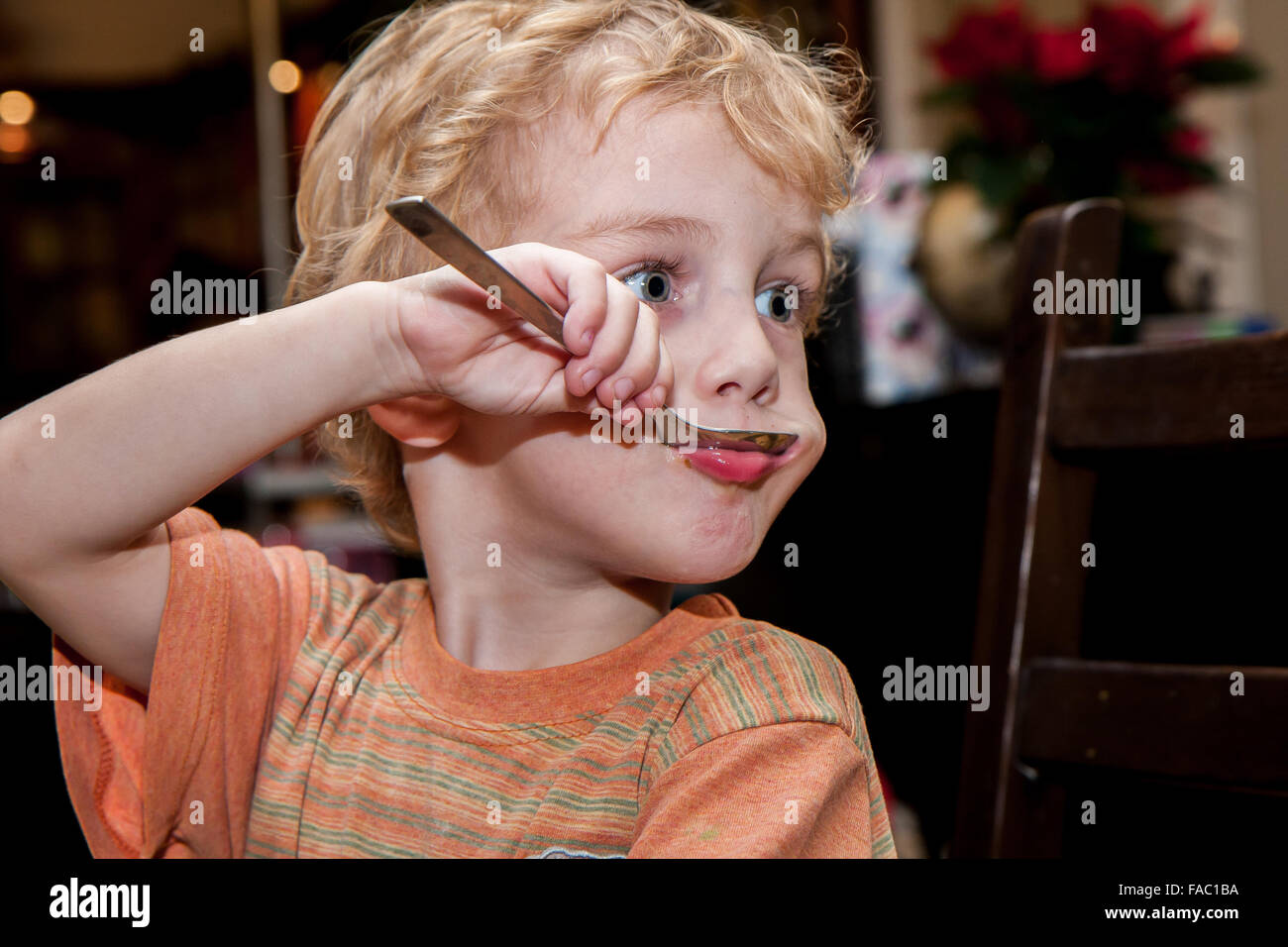 Junge Junge, blondes Haar macht Gesichter beim Suppe essen Stockfoto