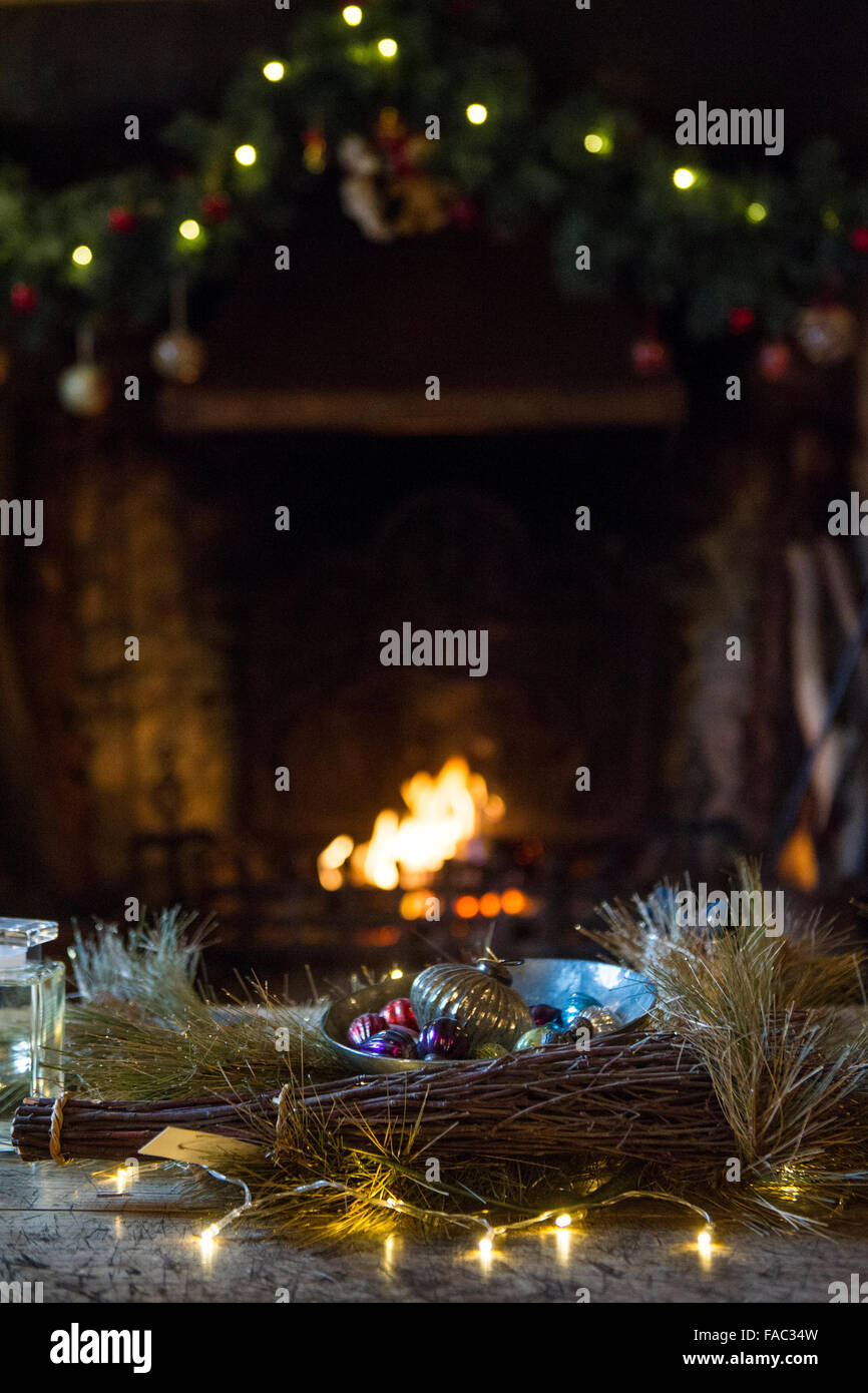 Weihnachtsschmuck vor und über dem offenen Feuer in einem Cottage auf dem Land Stockfoto