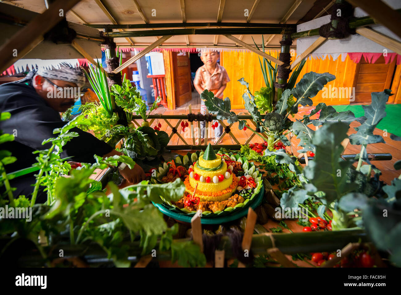 Ein ältester, der beim Festival Sarongge in Sarongge, West-Java, Indonesien, einen letzten Schliff für die Lebensmitteldekoration gibt. Stockfoto