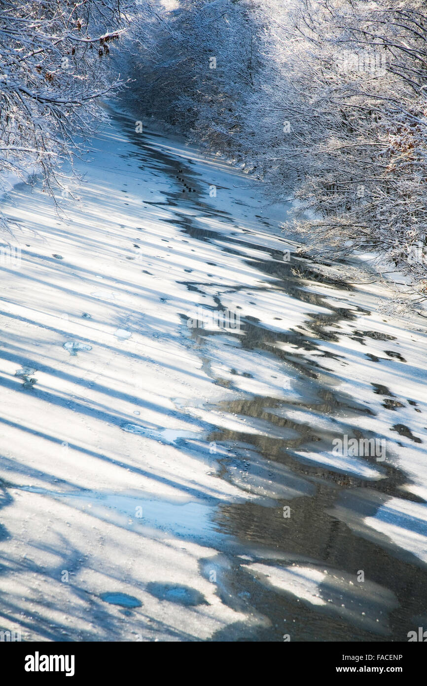 Sehen Sie auf einem zugefrorenen Fluss vom verschneiten Ufer. Stockfoto