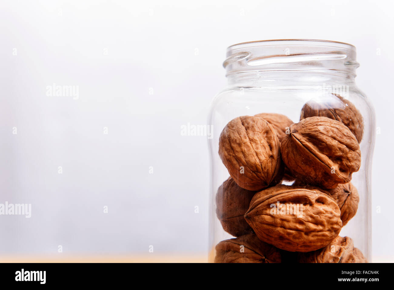 Walnüsse auf Glas jar über Holzoberfläche. Isoliert auf weißem Hintergrund Stockfoto