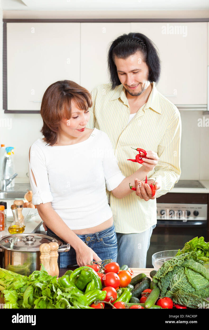 Positive Frau und Mann, Hinzufügen von Gewürzen oder Salz in den Topf geben und in der Küche zu Hause Stockfoto