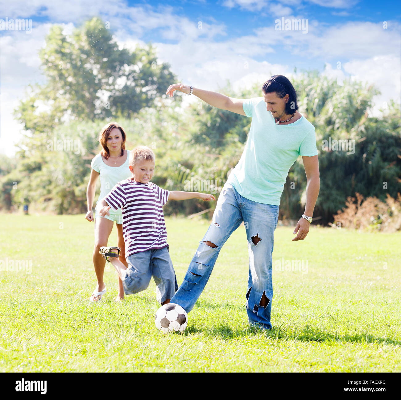 Familie von drei spielen mit Fußball im park Stockfoto