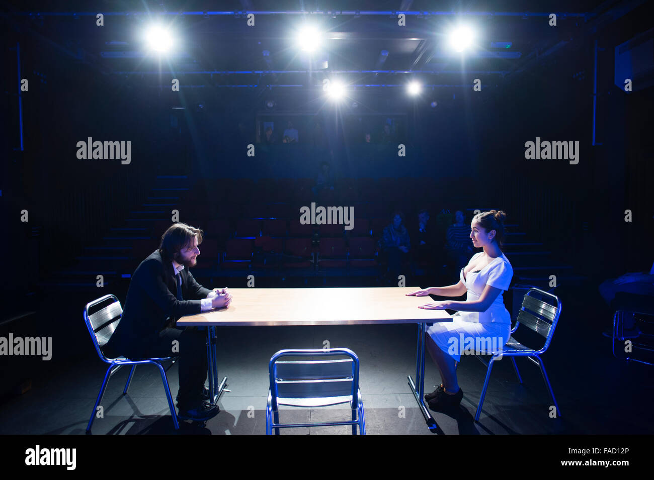 Theater studiert Bildung uk: zwei Jugendliche Schauspieler, ein Mann und eine Frau, auf der Bühne, sitzen einander gegenüber in einer Tabelle in einer Drama-Theater-Performance, Aberystwyth University, Wales UK Stockfoto