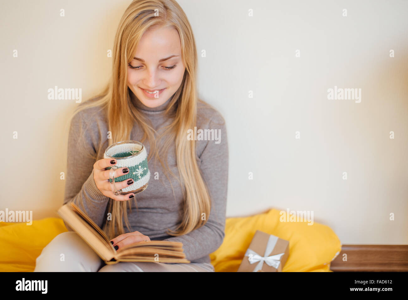 Blondes Mädchen trinken ihren Kaffee, esse Kekse und ein Buch lesen Stockfoto