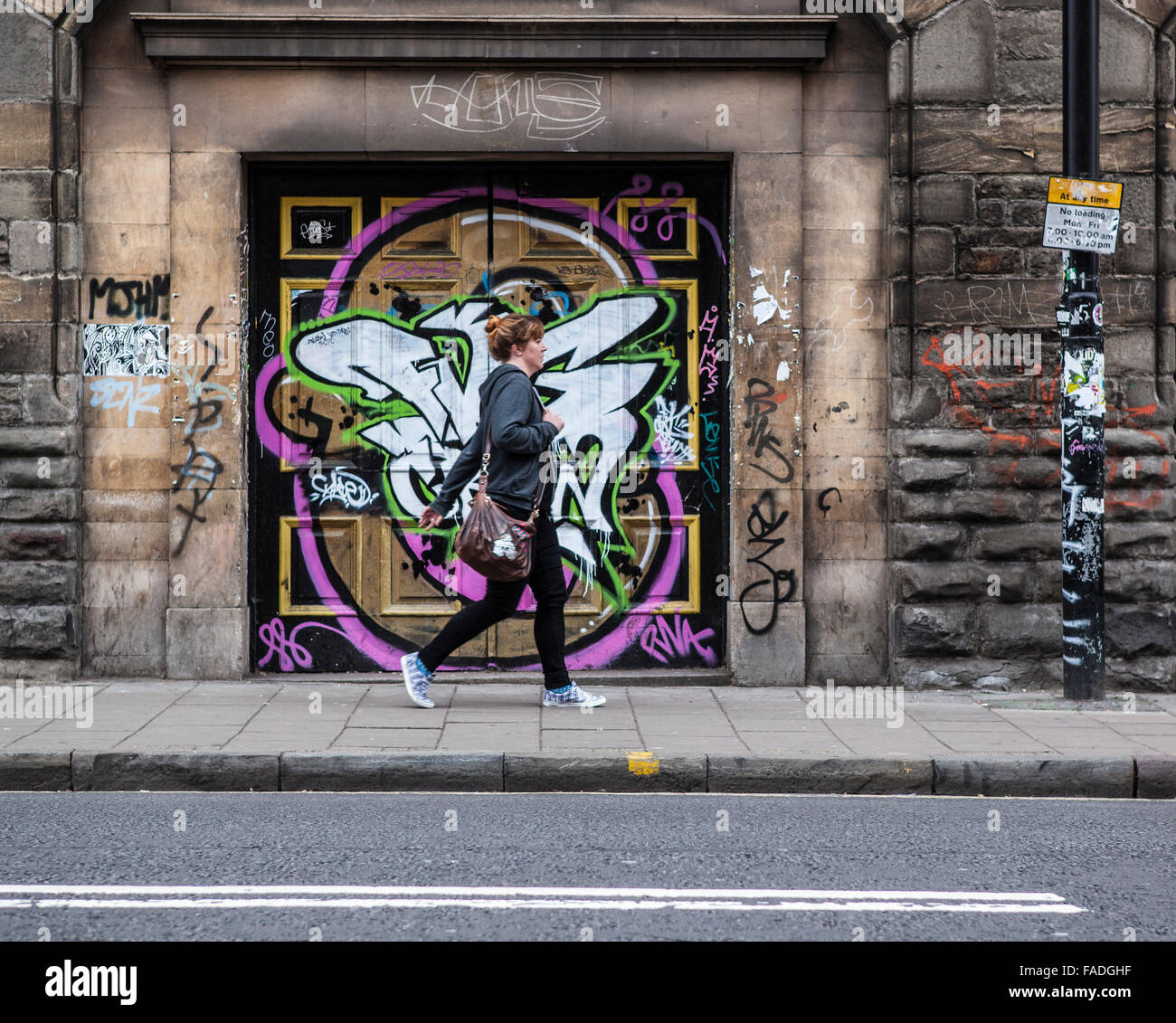 Frau zu Fuß vorbei an Straßenkunst Graffiti in Bristol Stockfoto