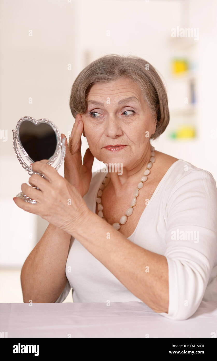 ältere Frau zu Hause in den Spiegel zu schauen Stockfoto