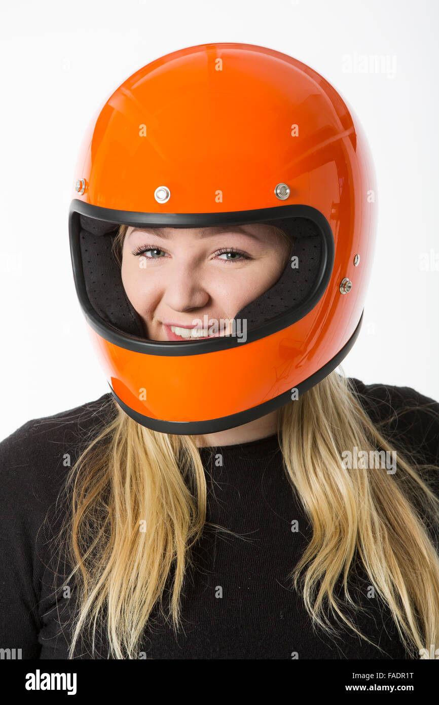 Nettes Mädchen mit blonden Haaren mit orange Motorradhelm. Studio auf weißem Hintergrund gedreht. Stockfoto