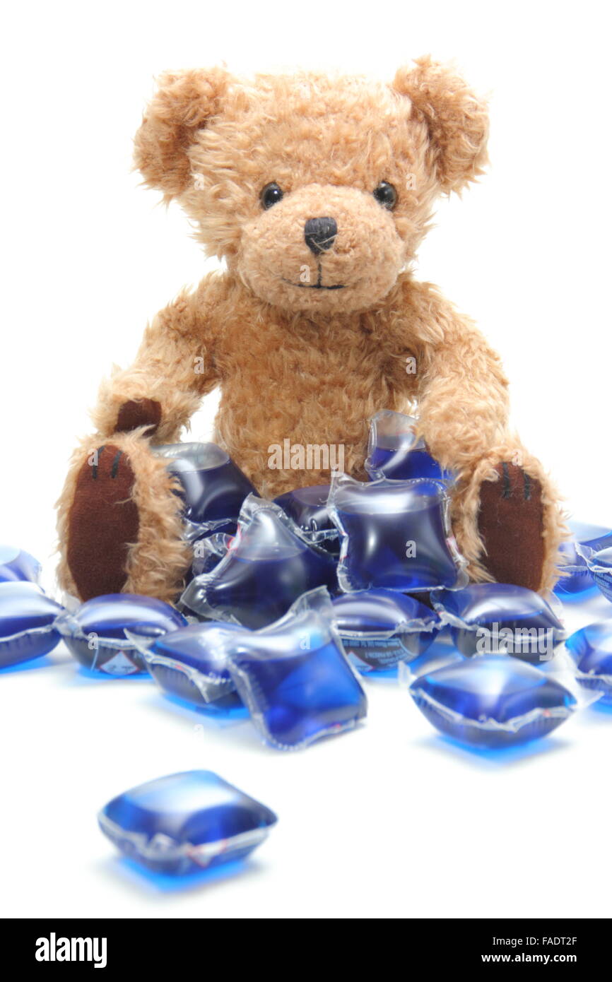 Flüssige Wäsche Waschmittel Kapseln umgeben ein Kind Teddybär - UK Stockfoto