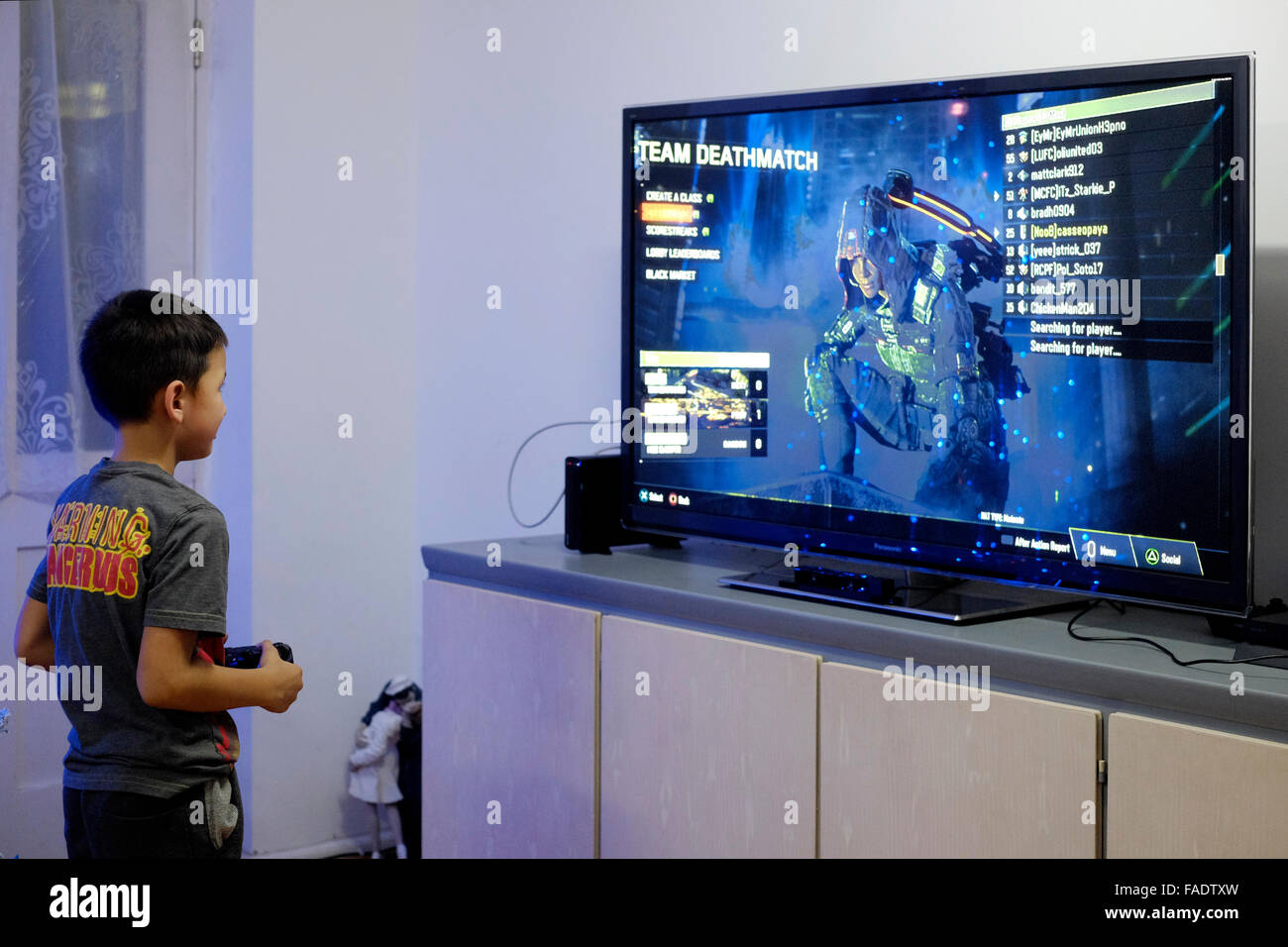 Jungen spielen Videospiel auf großen flachen Fernseher mit Flachbildschirm in England uk Stockfoto
