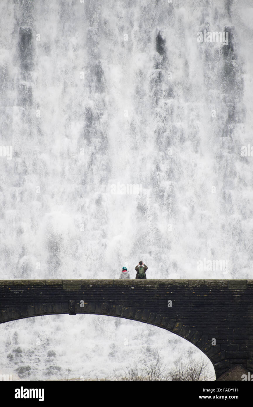 Elan-Tal, in der Nähe von Rhayader Powys Wales UK. 28. Dezember 2015.    Menschen auf der Fußgängerbrücke erhalten eine Nahaufnahme Blick nach Wochen des starken Regens das Wasser die Caban Coch-Talsperre in der Elan-Tal westlich von Rhayader Powys, Wales überragen.   Caban Coch ist die niedrigste Glied in einer Kette von 6 Talsperren und Stauseen, die vor hundert Jahren Fütterung in einem 73 Meile Schwerkraft angetrieben Aquädukt der Stadt Birmingham saubere Wasserversorgung gebaut. Das System insgesamt enthält 199 Millionen Tonnen Wasser Credit: Keith Morris/Alamy Live-Nachrichten Stockfoto