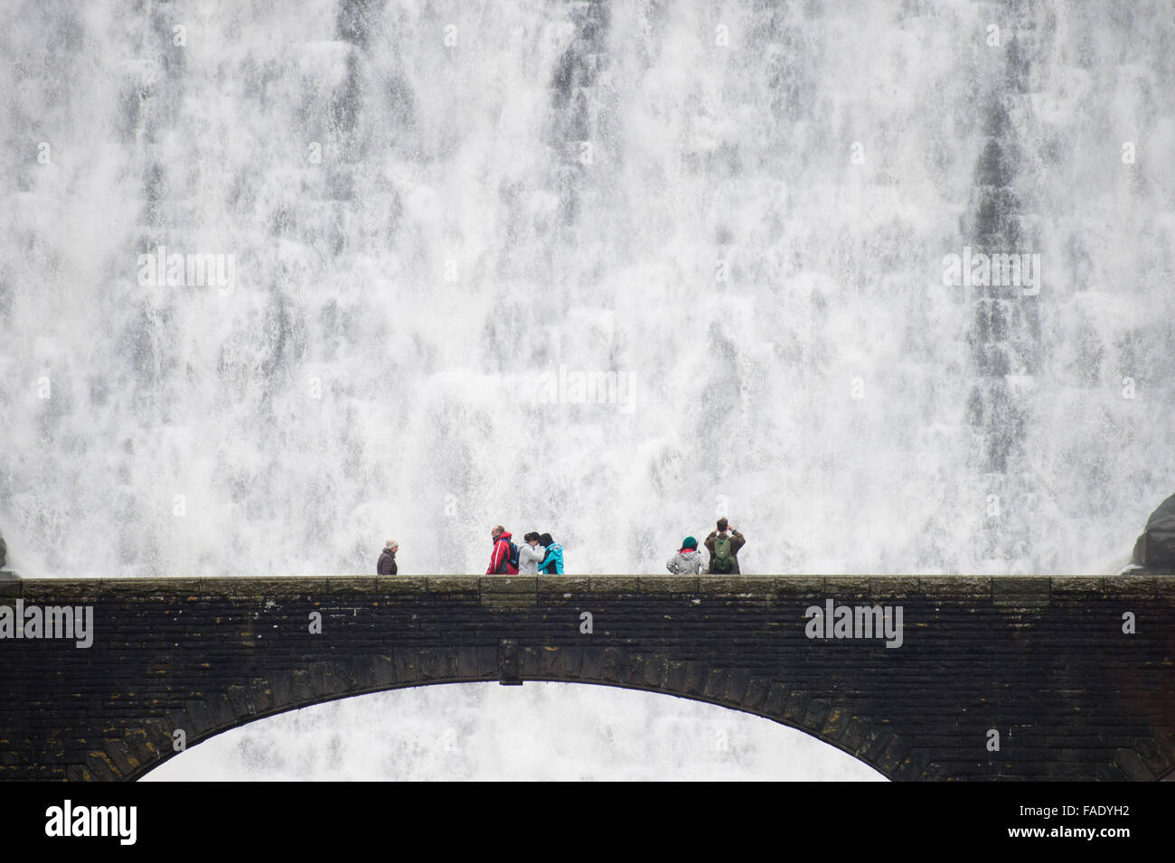 Elan-Tal, in der Nähe von Rhayader Powys Wales UK. 28. Dezember 2015.    Menschen auf der Fußgängerbrücke erhalten eine Nahaufnahme Blick nach Wochen des starken Regens das Wasser die Caban Coch-Talsperre in der Elan-Tal westlich von Rhayader Powys, Wales überragen.   Caban Coch ist die niedrigste Glied in einer Kette von 6 Talsperren und Stauseen, die vor hundert Jahren Fütterung in einem 73 Meile Schwerkraft angetrieben Aquädukt der Stadt Birmingham saubere Wasserversorgung gebaut. Das System insgesamt enthält 199 Millionen Tonnen Wasser Credit: Keith Morris/Alamy Live-Nachrichten Stockfoto