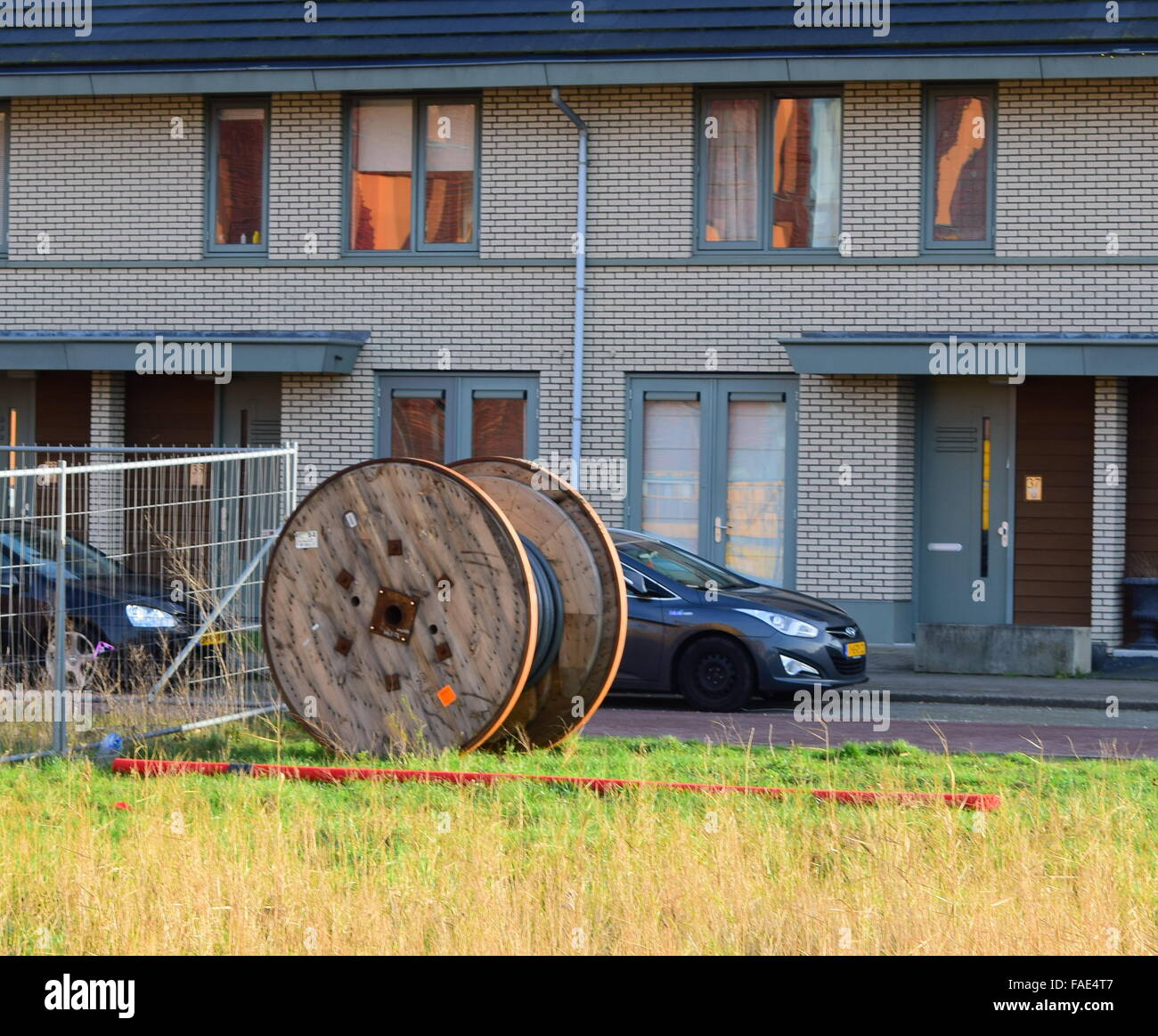 Eine hölzerne Riesenrad für elektrische Leitungen sitzen in einem kleinen Feld vor einem Apartment-Komplex. Stockfoto