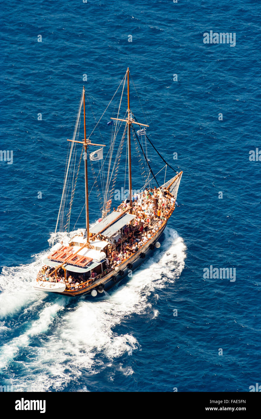 Kykladen, Santorini. Verpackt touristische Griechische Segel und Motor touristischen Ausflug segeln Pflügen durch tiefblaue Meer mit Wake hinter sich. Luftaufnahme. Stockfoto Kykladen, Santorini. Verpackt touristische Griechische Segel und Motor touristischen Ausflug segeln Pflügen durch tiefblaue Meer mit Wake hinter sich. Luftaufnahme. Stockfoto