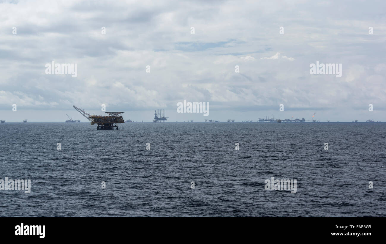 Viele Offshore-Bohrinseln am Horizont abseits der Küste von Brunei Darussalam, South China Sea. Bewölkter Himmel. Stockfoto
