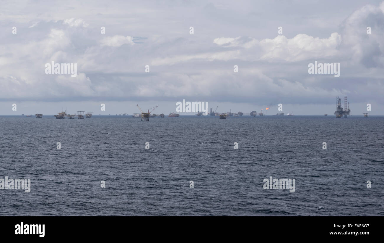 Viele Offshore-Bohrinseln am Horizont abseits der Küste von Brunei Darussalam, South China Sea. Bewölkter Himmel. Stockfoto