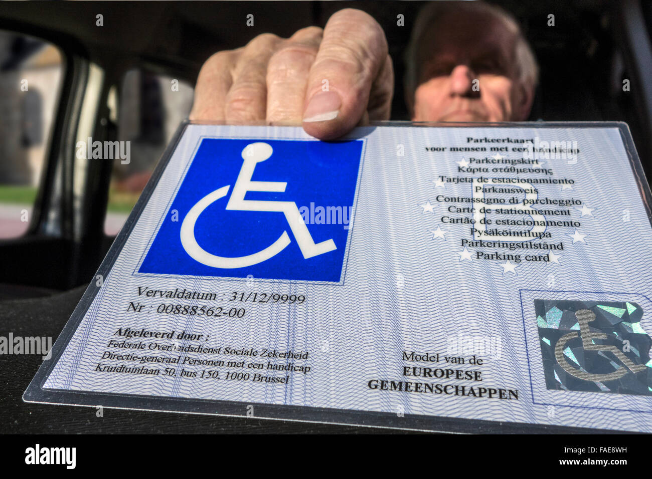 Älteren Mann setzen EU-Parkausweis für Menschen mit Behinderungen – Blue Badge - hinter der Windschutzscheibe des Autos behindert Stockfoto