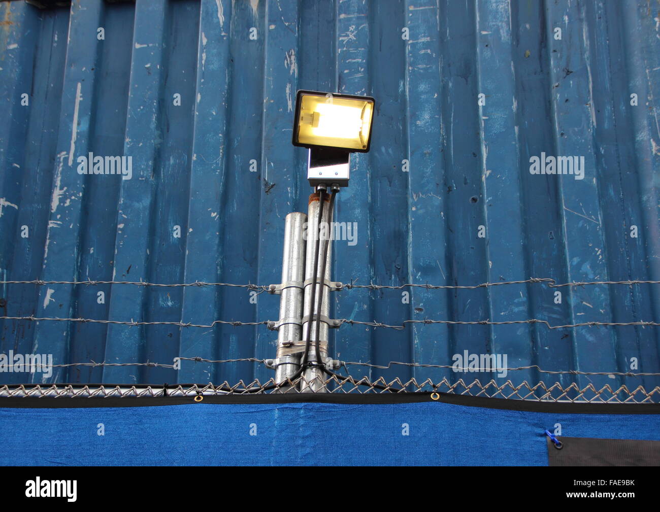 Überwachung-Scheinwerfer auf blauem Metall Hintergrund mit Barbwire Stockfoto