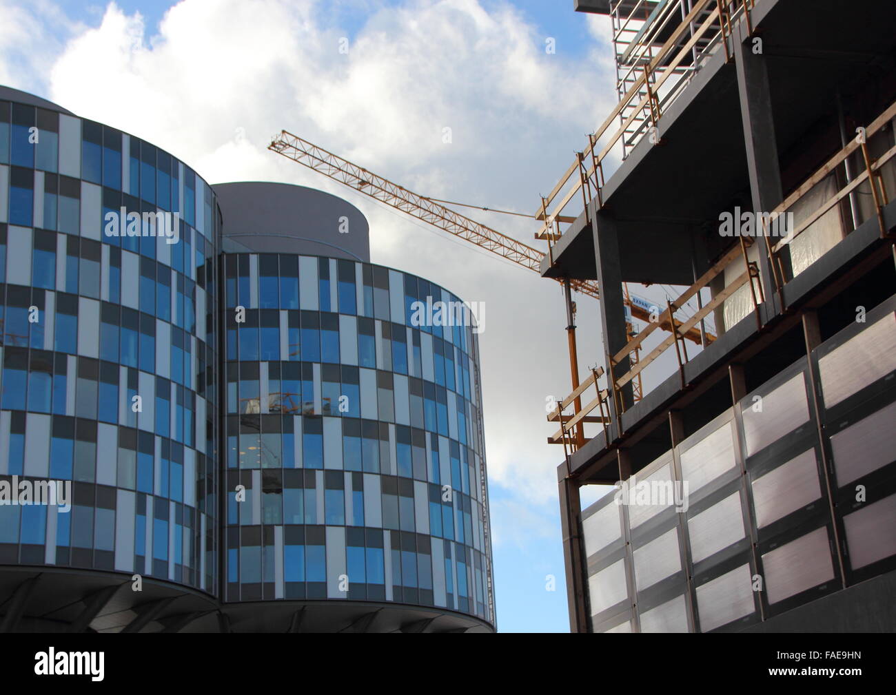 Runde blaue moderne Gebäude und Baustelle mit dem Erstellen von Website-Kran. Wohnungen sind gebaut um einen geschlossenen Getreidespeicher Stockfoto