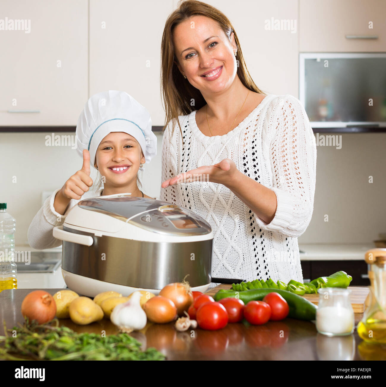 Slow Cooker helfende Mutter und lächelndes Mädchen zur Vorbereitung Abendessen in Küche zu Hause Stockfoto