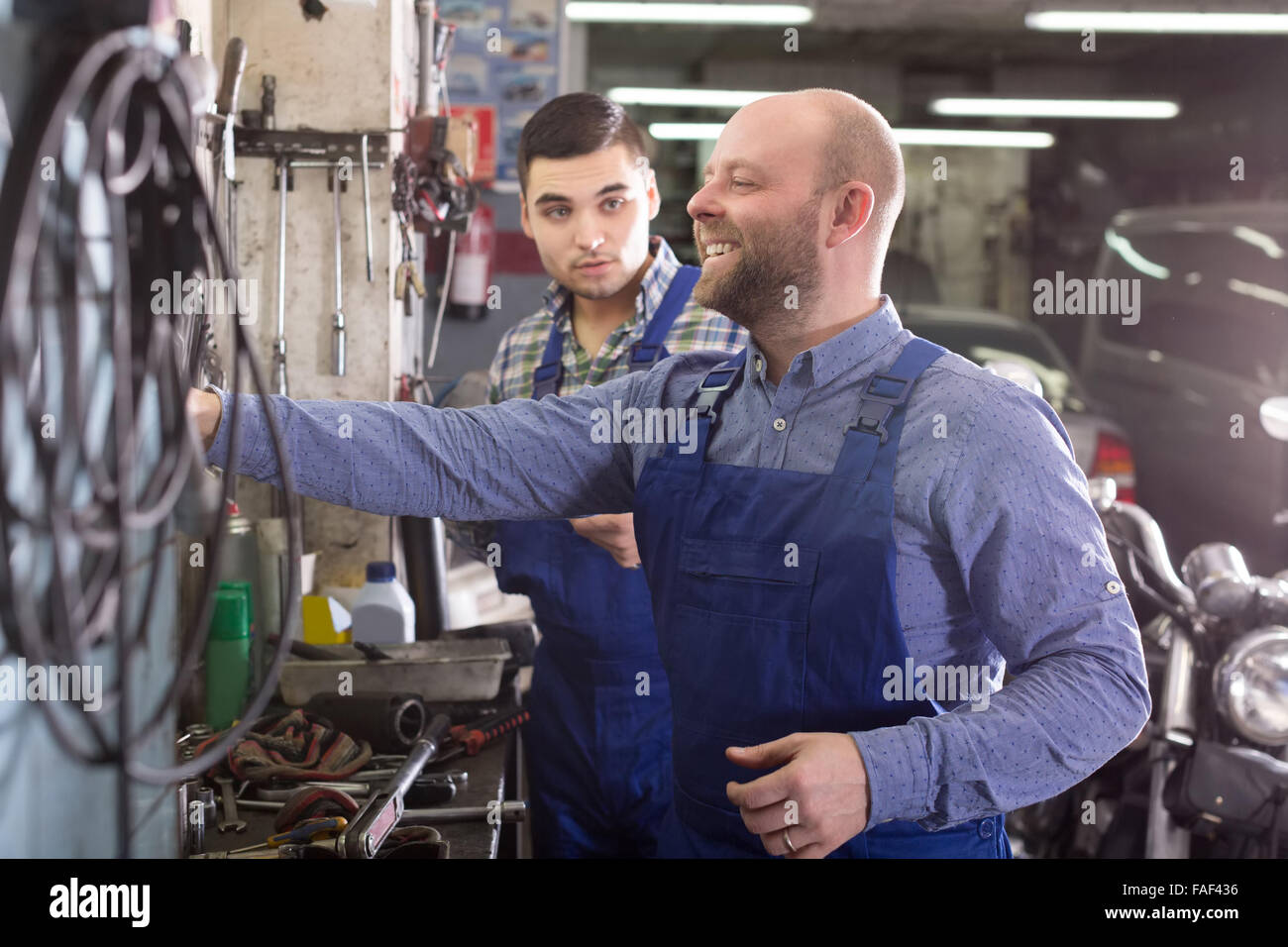 Europäische Männer in Overalls arbeiten bei Carshop Lächeln Stockfoto