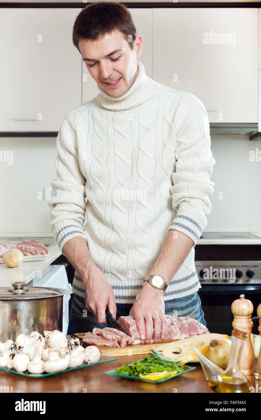 Glücklich, gut aussehender Mann kochen Französisch-Stil  Kalbfleisch-Schneiden von Fleisch Stockfotografie - Alamy