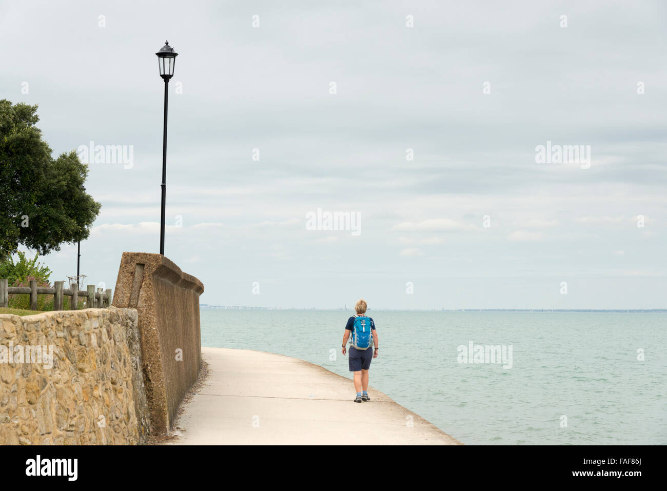 Eine Frau zu Fuß auf dem Küstenpfad in der Nähe von Meerblick auf der britischen Isle Of Wight an einem bewölkten Sommertag Stockfoto