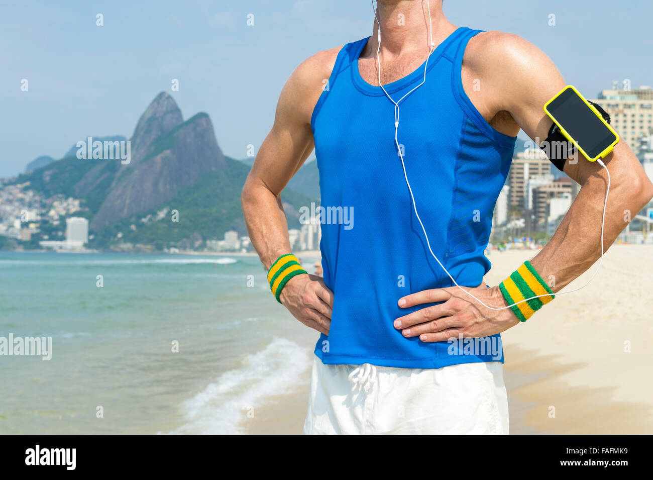 Sportler, die Handy-Technologie Armbinde tragen steht motivierende Musik im Freien auf Ipanema Strand Rio de Janeiro Stockfoto