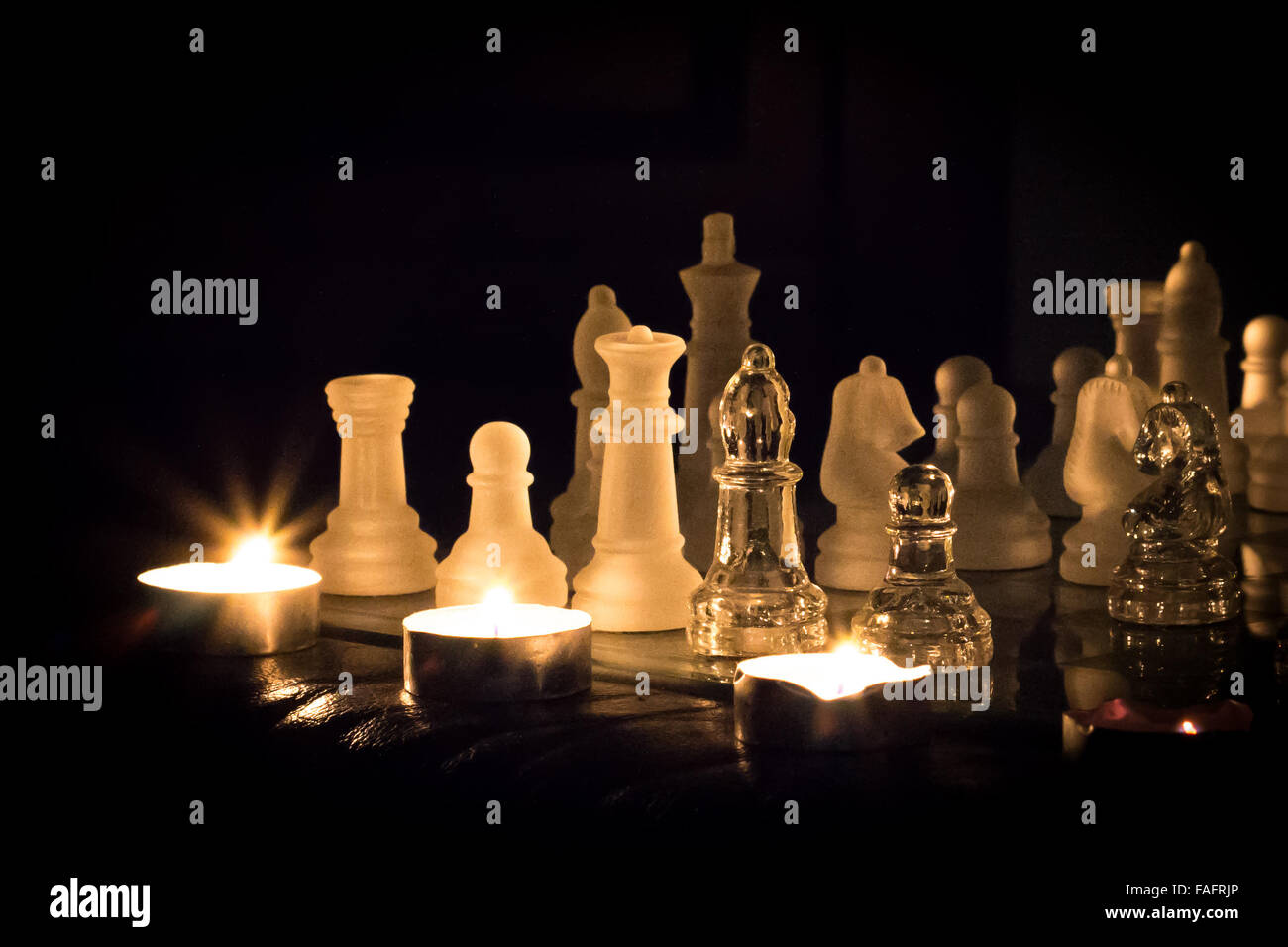 Glas-Schachspiel von Teelichtern beleuchtet. Stockfoto