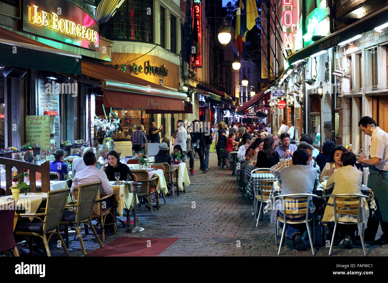 Restauranttische auf dem Bürgersteig in der Rue des Bouchers, einer Fußgängerzone in der Altstadt von Brüssel in Rücken austreten. Stockfoto