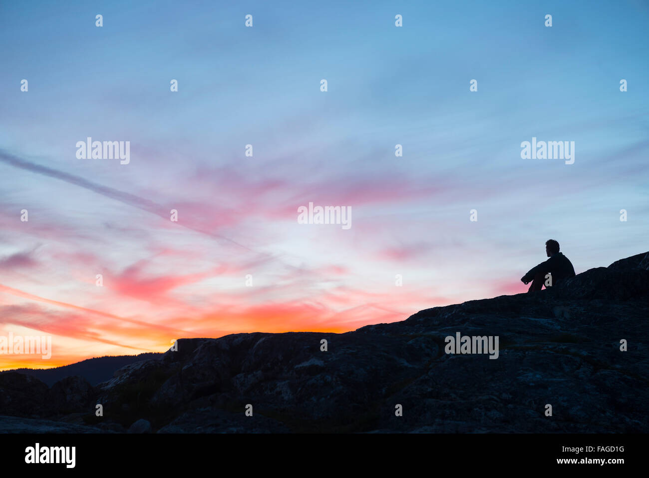 Ein einsamer Mann einen wunderschönen Sonnenuntergang genießen Stockfoto