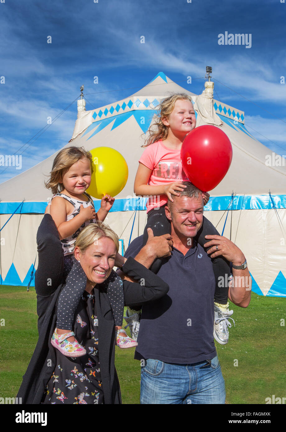 Eine glückliche Familie verlassen das Zirkuszelt nach einem Ausflug in den Zirkus in Bucht Sonne mit blauem Himmel und Ballon Stockfoto