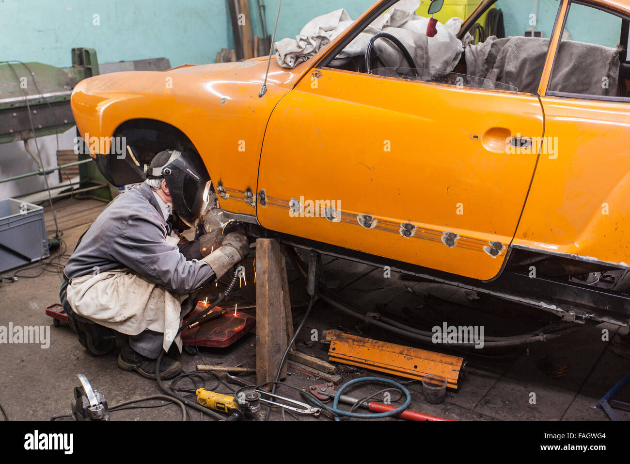 Karosseriebauer stellt ein Oldtimer VW Karmann Ghia. Schweißarbeiten an der Karosserie des Fahrzeugs. Stockfoto