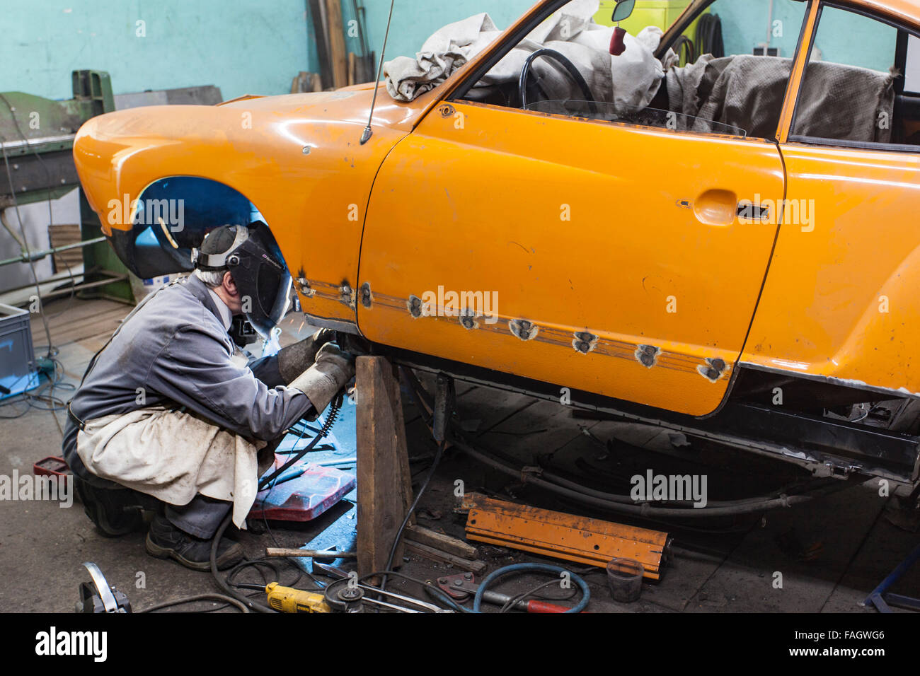 Karosseriebauer stellt ein Oldtimer VW Karmann Ghia. Schweißarbeiten an der Karosserie des Fahrzeugs. Stockfoto
