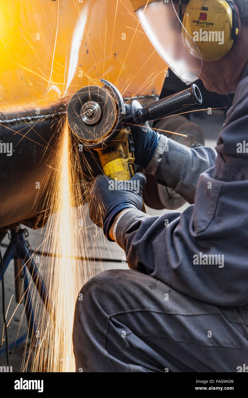 Karosseriebauer stellt ein klassisches Auto VW Karmann Ghia. Schweißnähte werden mit Winkelschleifer verarbeitet. Stockfoto