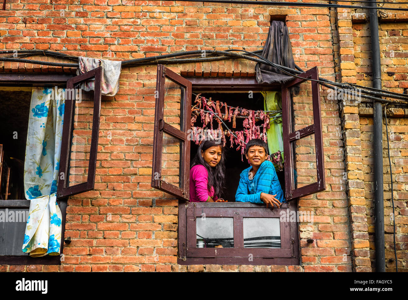 Zwei Kinder Lächeln auf den Lippen und der Blick aus einem Fenster in Nepal Stockfoto