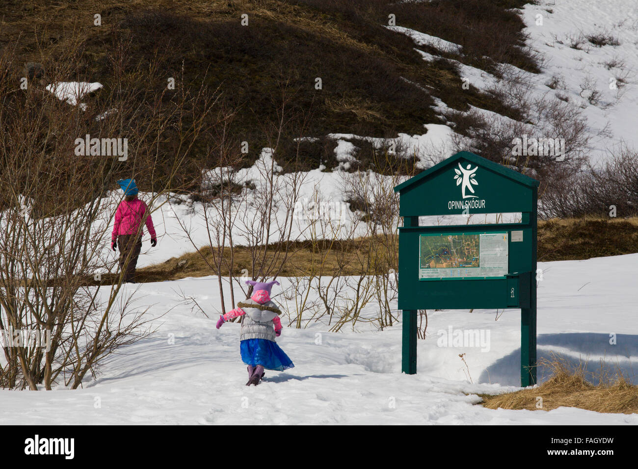Eine Familie und Kleinkind in bunten Kleidern gekleidet gehen in einem öffentlichen Park am Stadtrand von Isafjördur, Westfjorde, Island Stockfoto